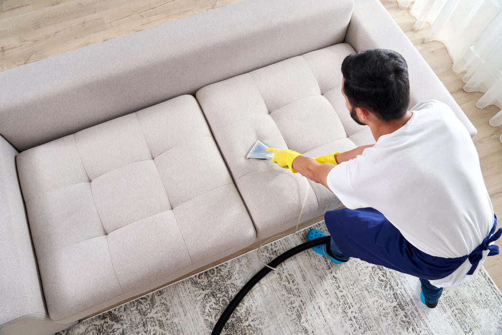 Mann macht Couch mit Dampfreiniger sauber