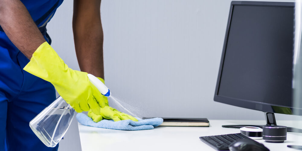 Putzkraft reinigt Schreibtisch