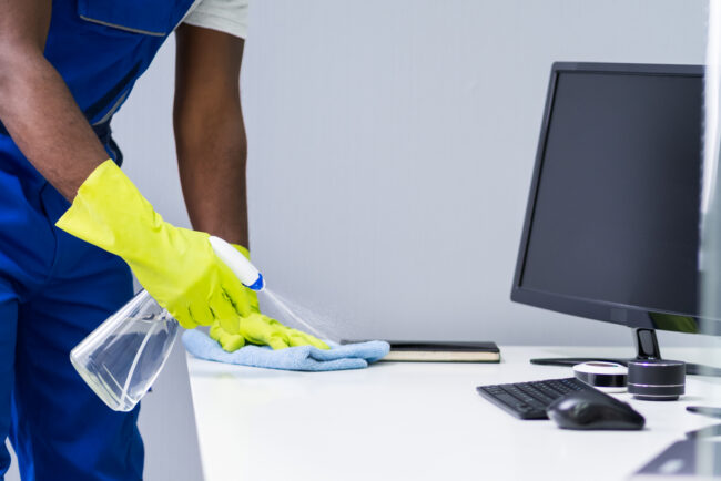 Putzkraft reinigt Schreibtisch Putzkraft reinigt Schreibtisch