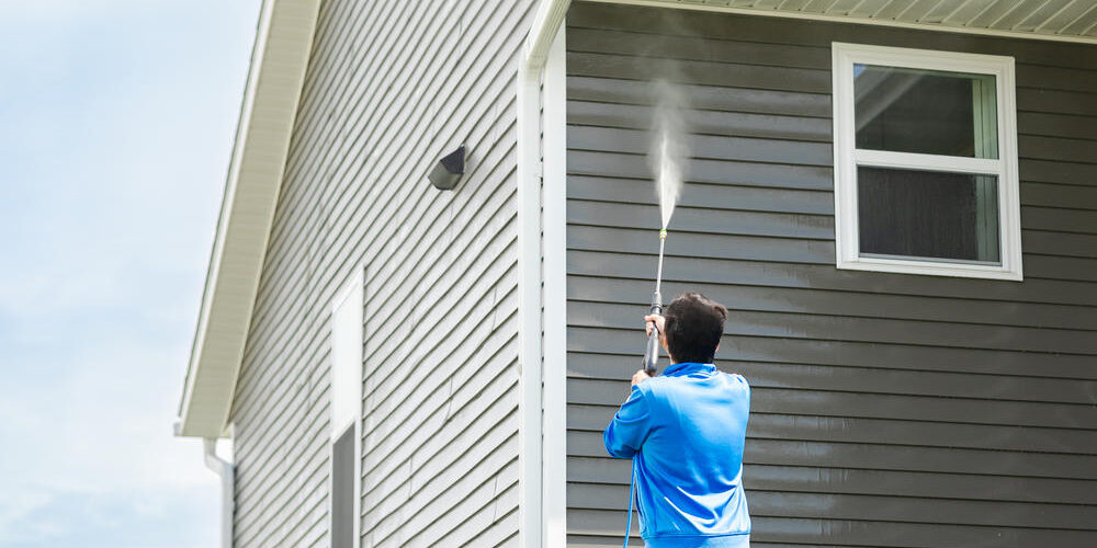 Mann-reinigt-mit-Hochdruckdüse-die-Aussenfassade