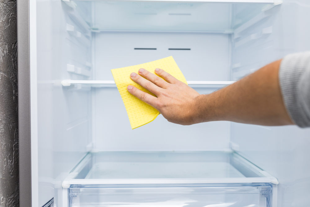 Mann-reinigt-die-inneren-Fächer-des-Kühlschrankes