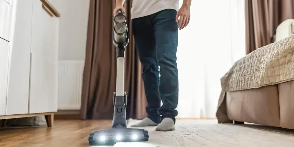 Mann staubsaugt Wohnzimmer