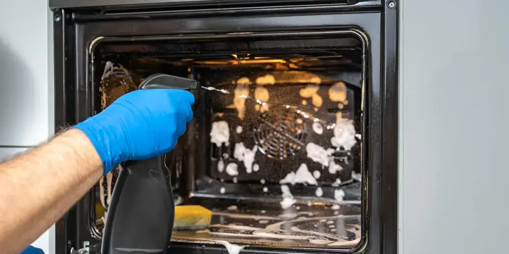 Hausreinigung Mann macht Backofen sauber Hausreinigung Mann macht Backofen sauber
