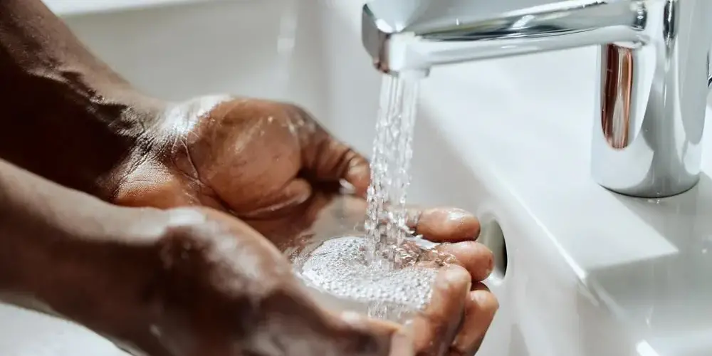 Mann hält Hände unter fliessendem Wasser Mann hält Hände unter fliessendem Wasser