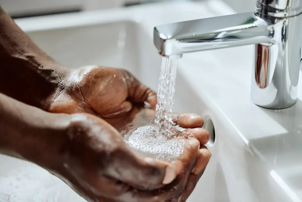 Mann hält Hände unter fliessendem Wasser