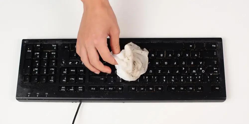 Mann reinigt die Computertastatur Mann reinigt die Computertastatur