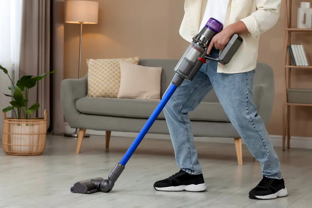 Mann staubsaugt Wohnzimmer